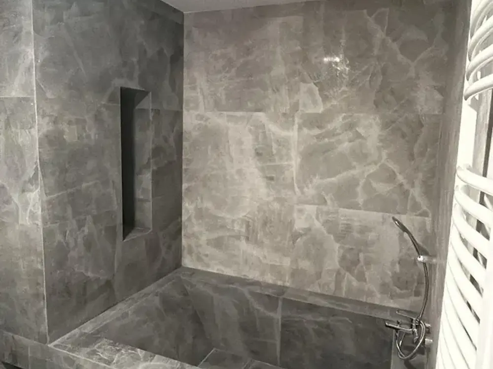 Mismo hueco de bañera terminado con revestimiento gris efecto mármol, reforma de baño en Santiago