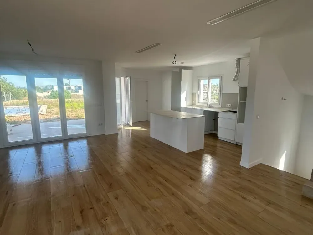 Mismo salón terminado con suelo de tarima y cocina abierta instalada, reforma integral en Santiago