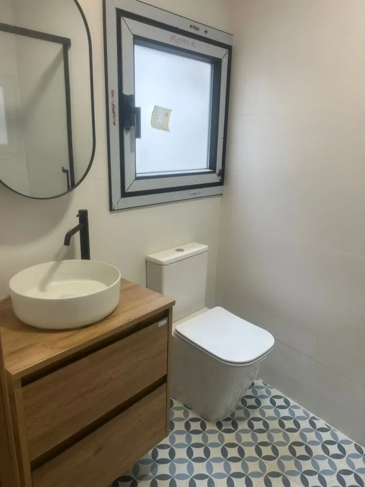 Baño reformado en Santiago con lavabo sobre encimera de madera y suelo hidráulico azul