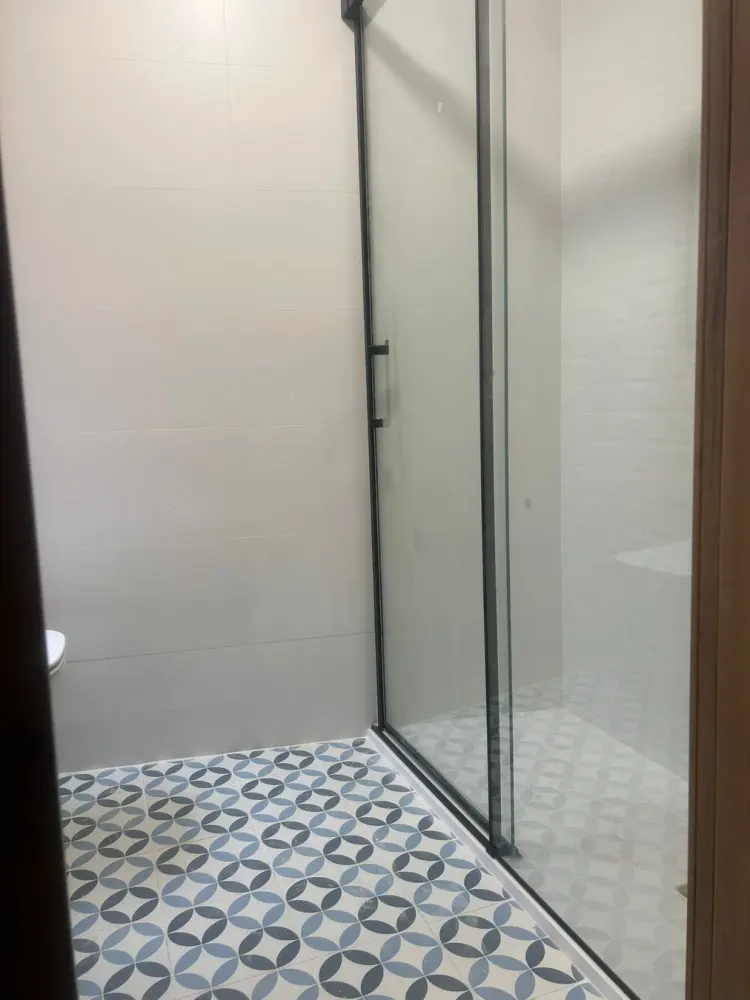 Baño reformado en Santiago con suelo hidráulico y revestimiento claro