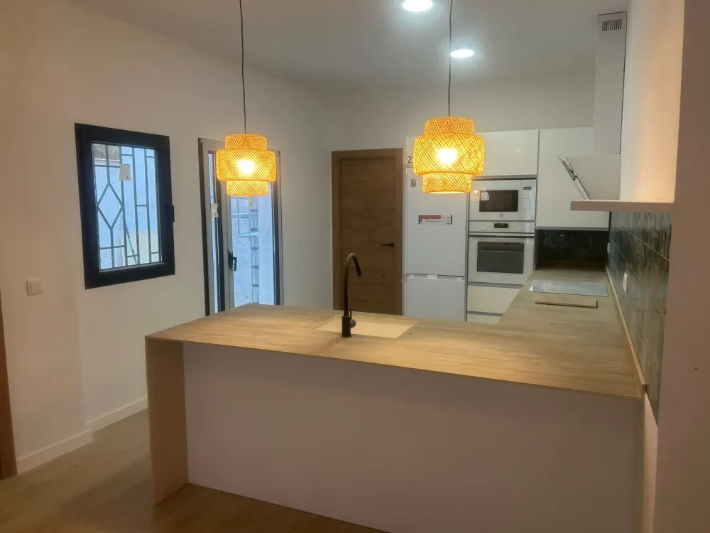 Reforma de cocina en Santiago con isla y encimera de madera, cocina abierta al salón