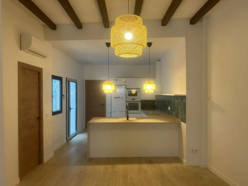 Reforma de cocina abierta en Santiago con vigas de madera vistas