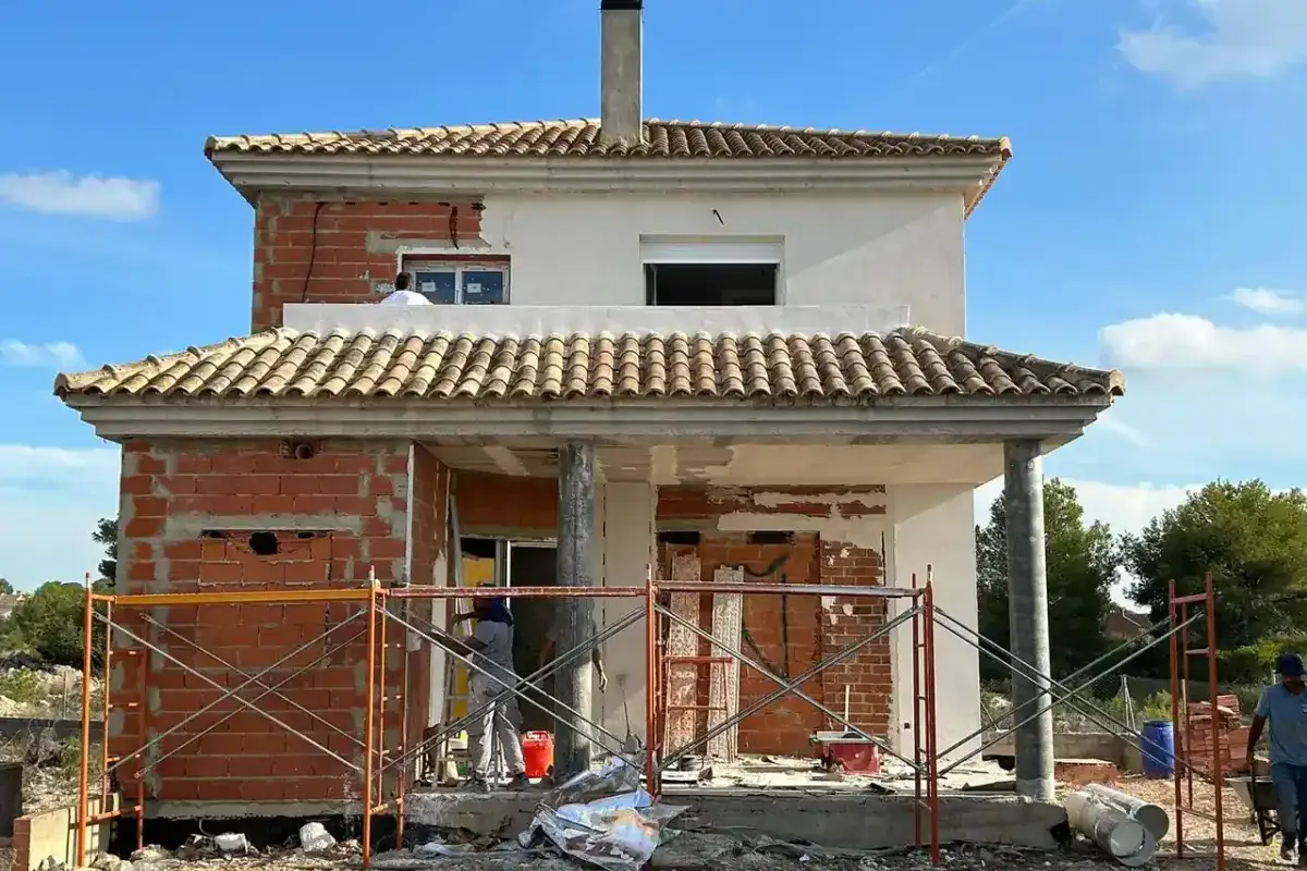 Fachada de vivienda unifamiliar en obra con andamio en Brión